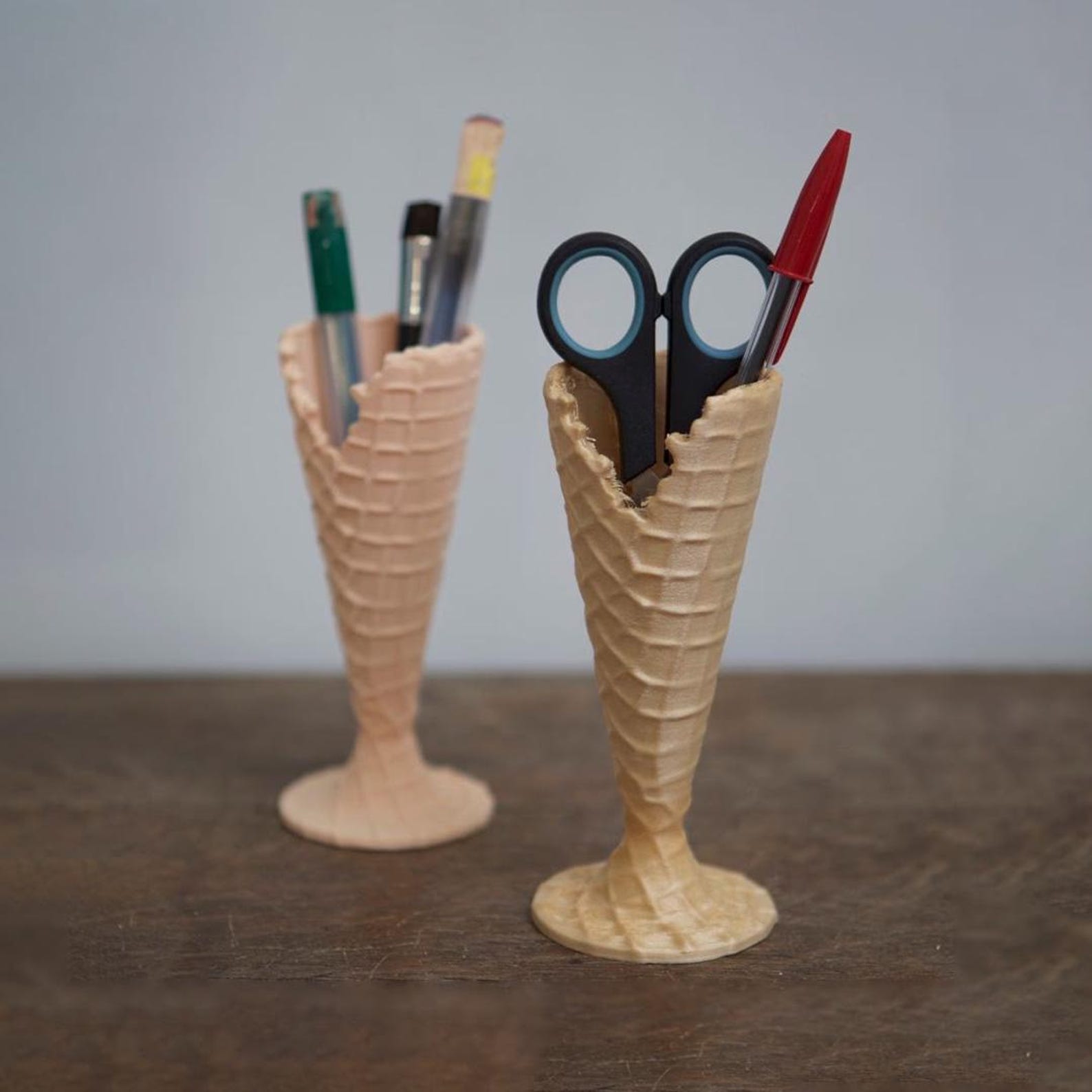 Ice cream cone shaped 3D printed pen holder with pens on a desk