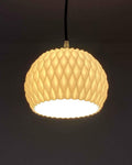 Wavy 3D printed sculptural pendant lamp shade hanging over a dining table
