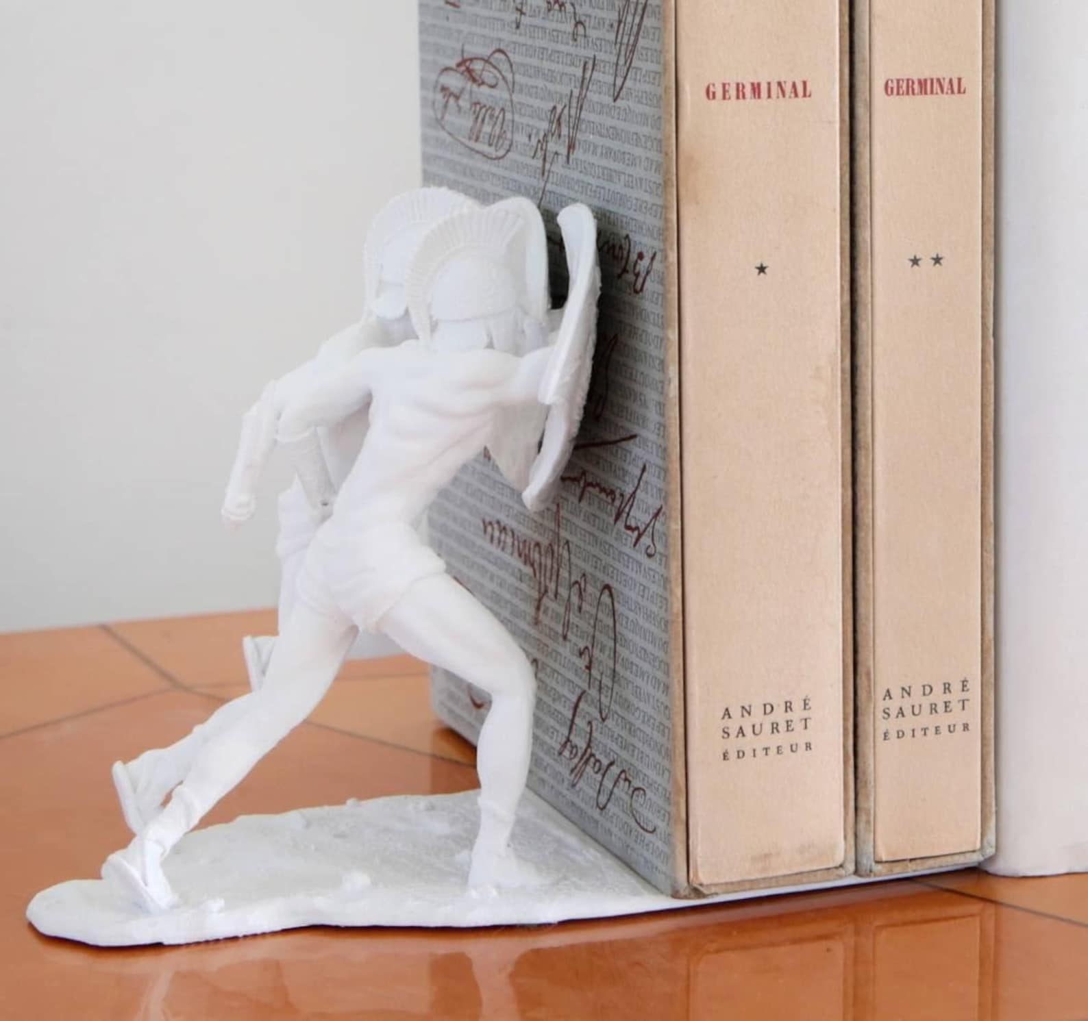 Spartan helmet 3D printed bookend holding a row of books