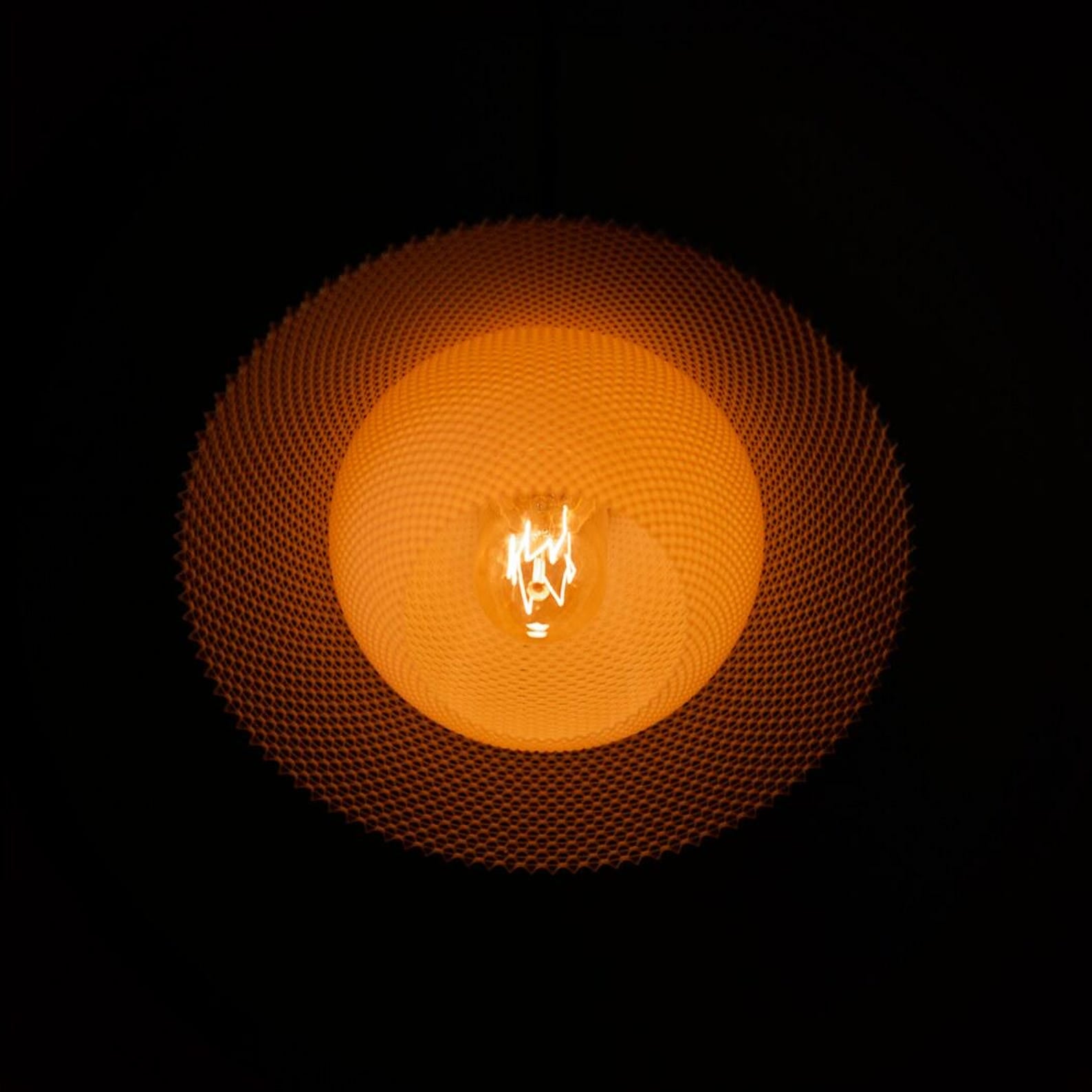 Orson saucer pendant glowing over a table