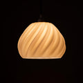 Dryft 3D printed sculptural pendant lamp glowing in a modern living room