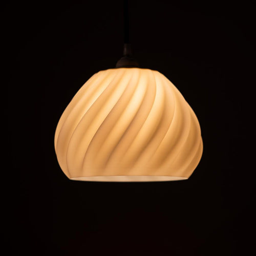 Dryft 3D printed sculptural pendant lamp glowing in a modern living room