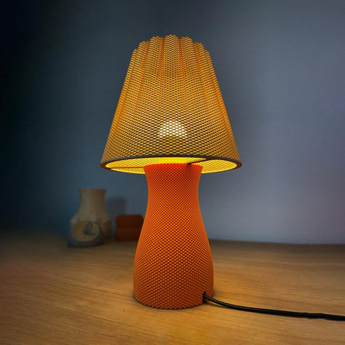 Carmen 3D printed sculptural ripple table lamp glowing on a nightstand