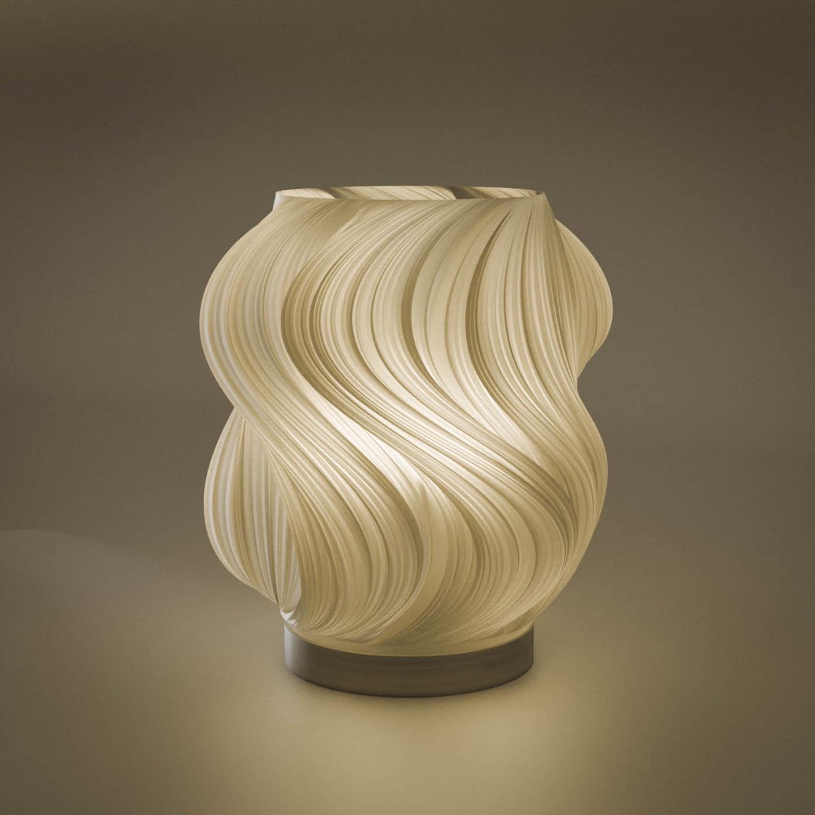 Cream wave table lamp lit and casting a warm glow